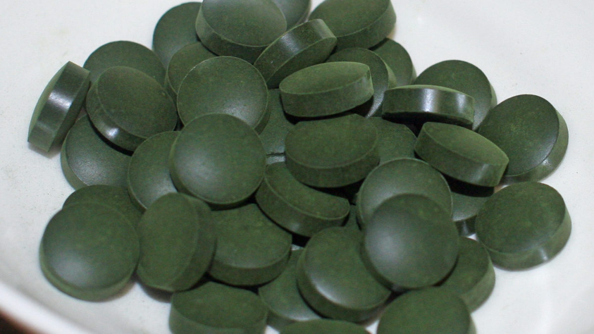 Tmavě zelené tablety spiruliny v bílé misce