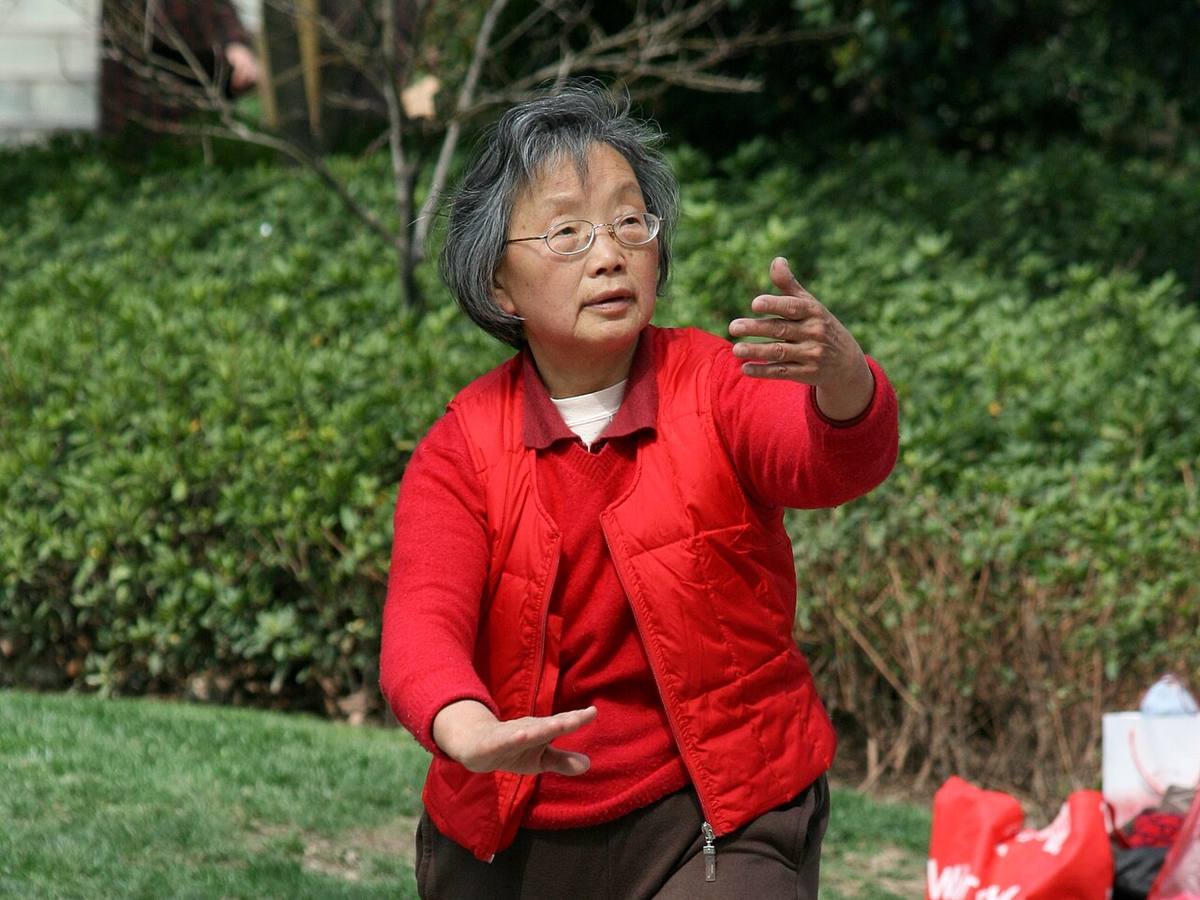 Starší žena v parku cvičí tai chi