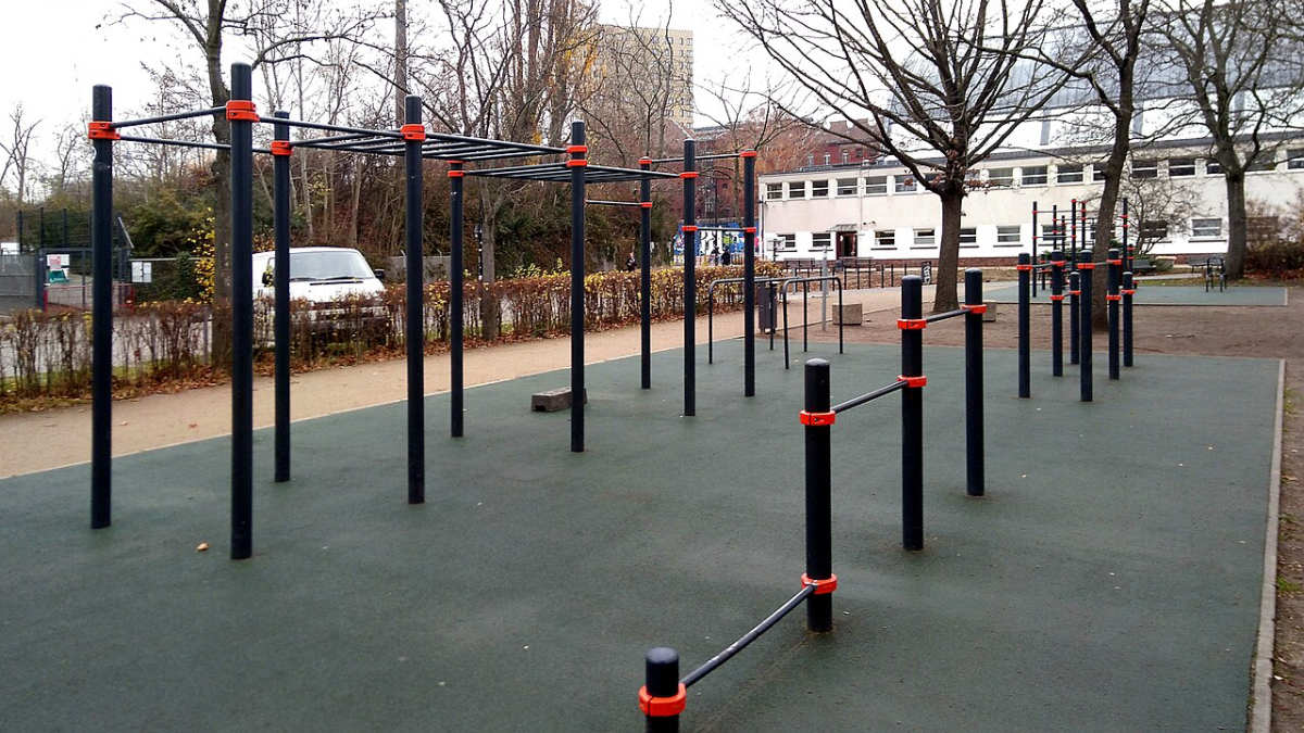 Venkovní street workout hřiště s hrazdami a bradly na pryžovém povrchu v městském parku