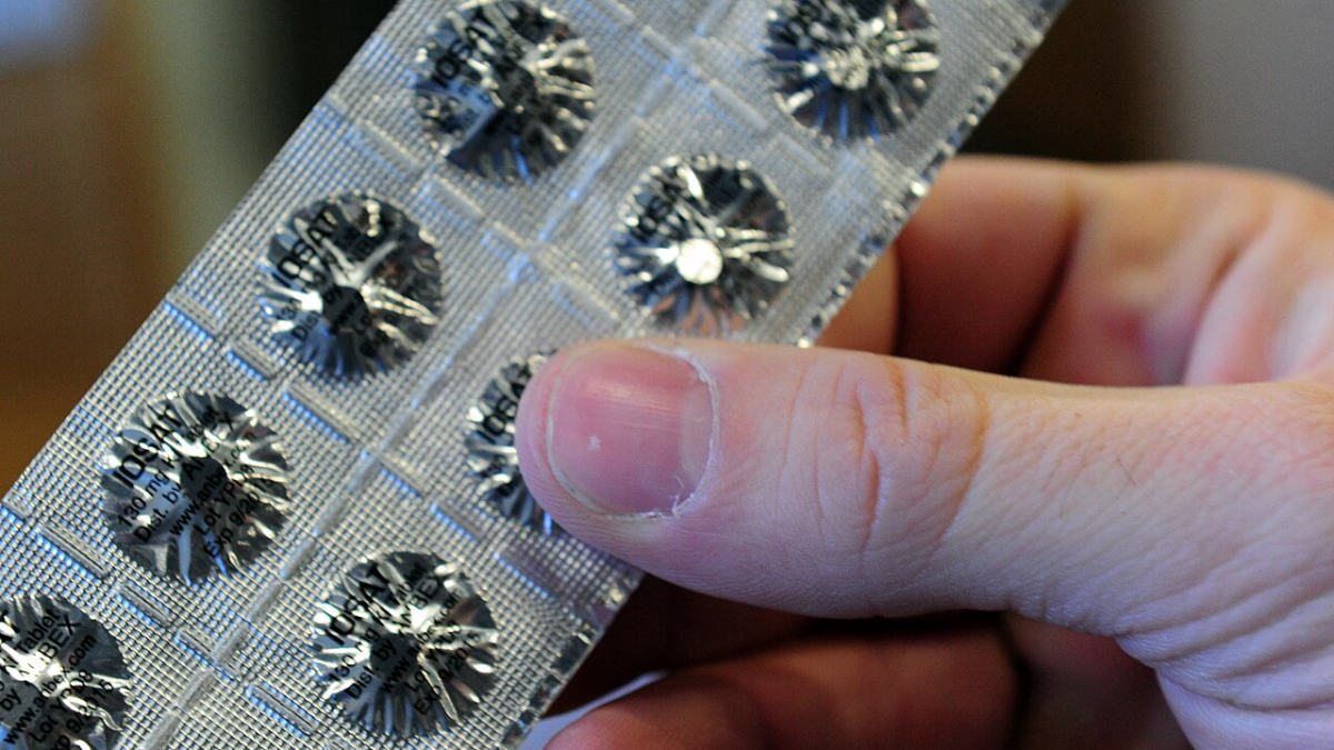 Ruka drží stříbrný blistr s tabletami jodidu draselného 130 mg