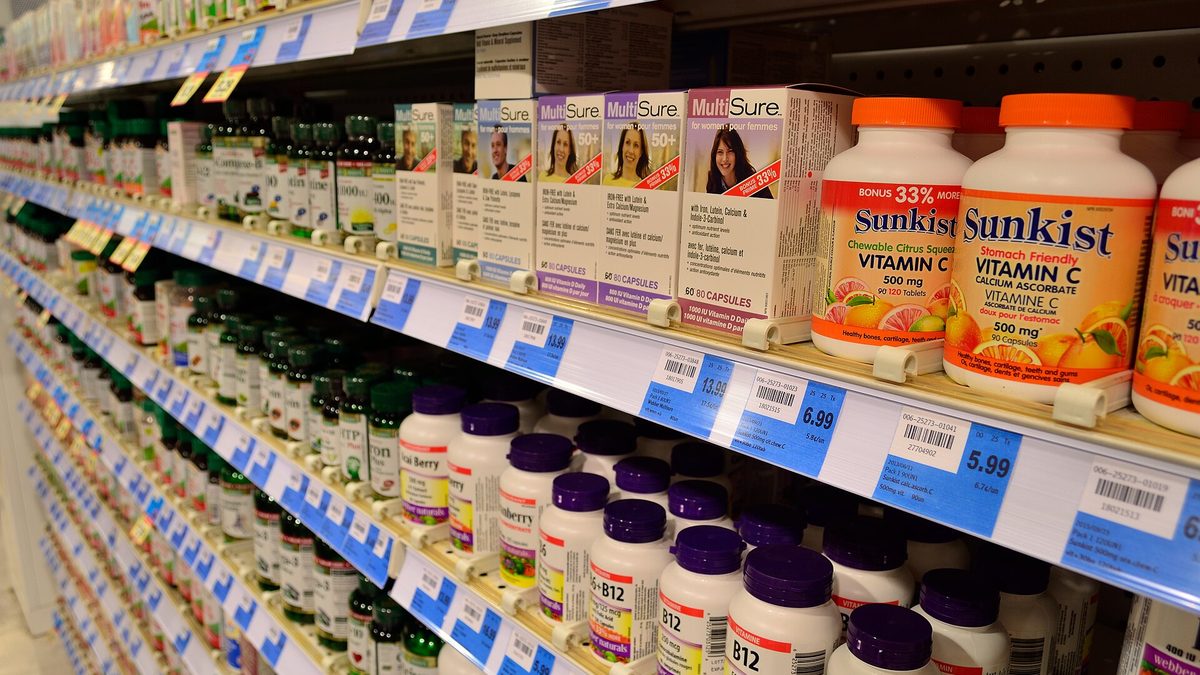 Regál s doplňky stravy v lékárně, dole lahvičky vitaminu B12