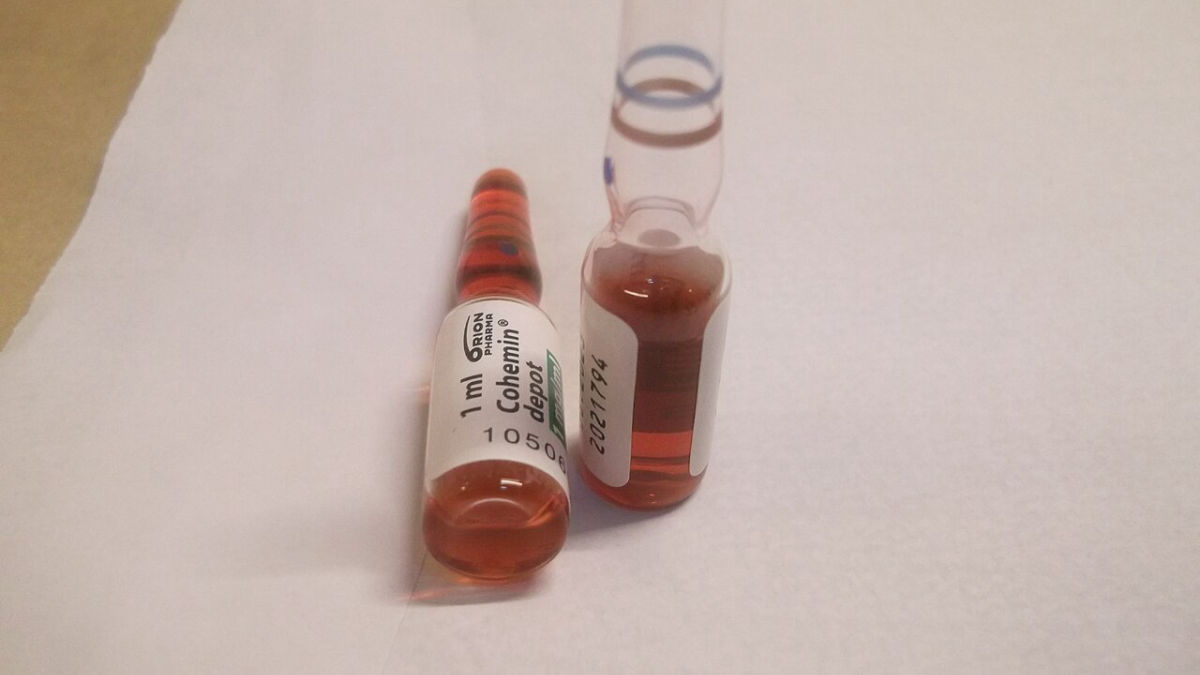 Dvě skleněné ampule s červeným roztokem vitaminu B12 k injekci