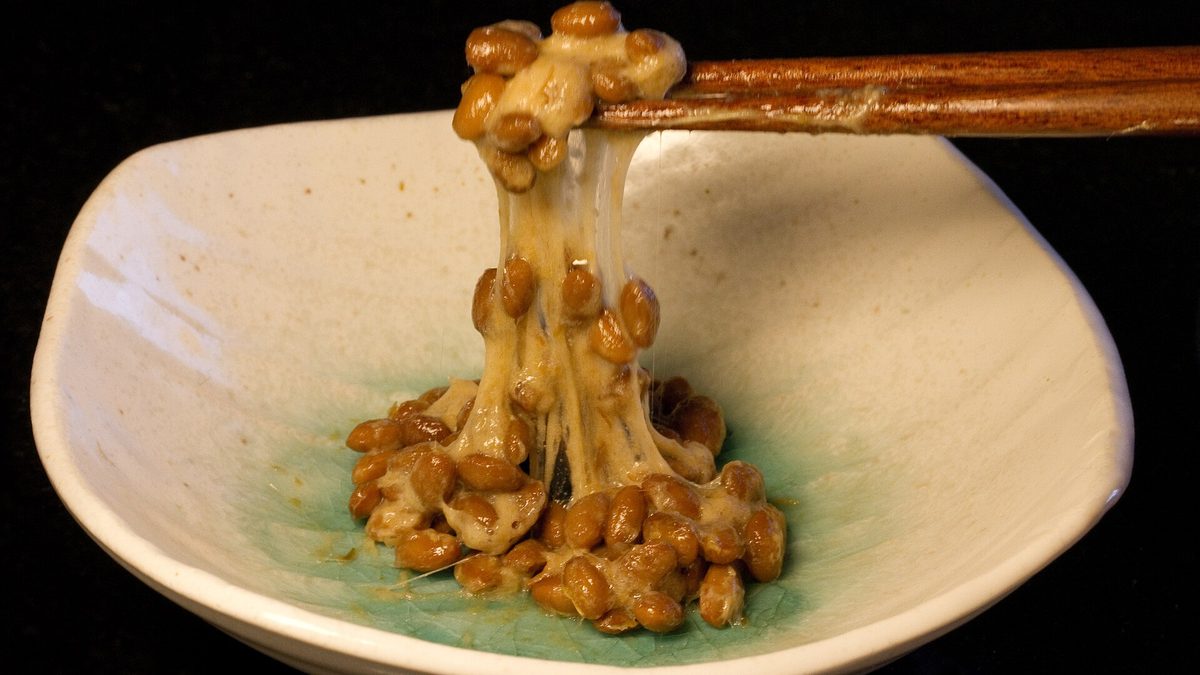 Natto, kvašené sójové boby, nabrané hůlkami z misky